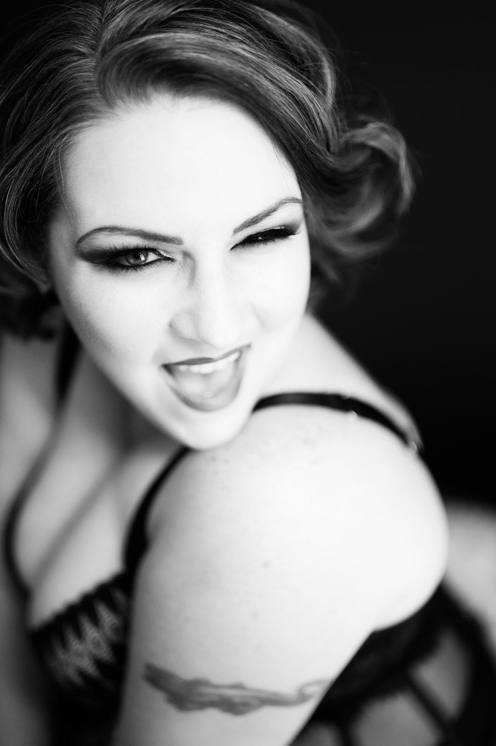 cute fun playful woman winking at camera for boudoir black and white portrait in lansing, michigan