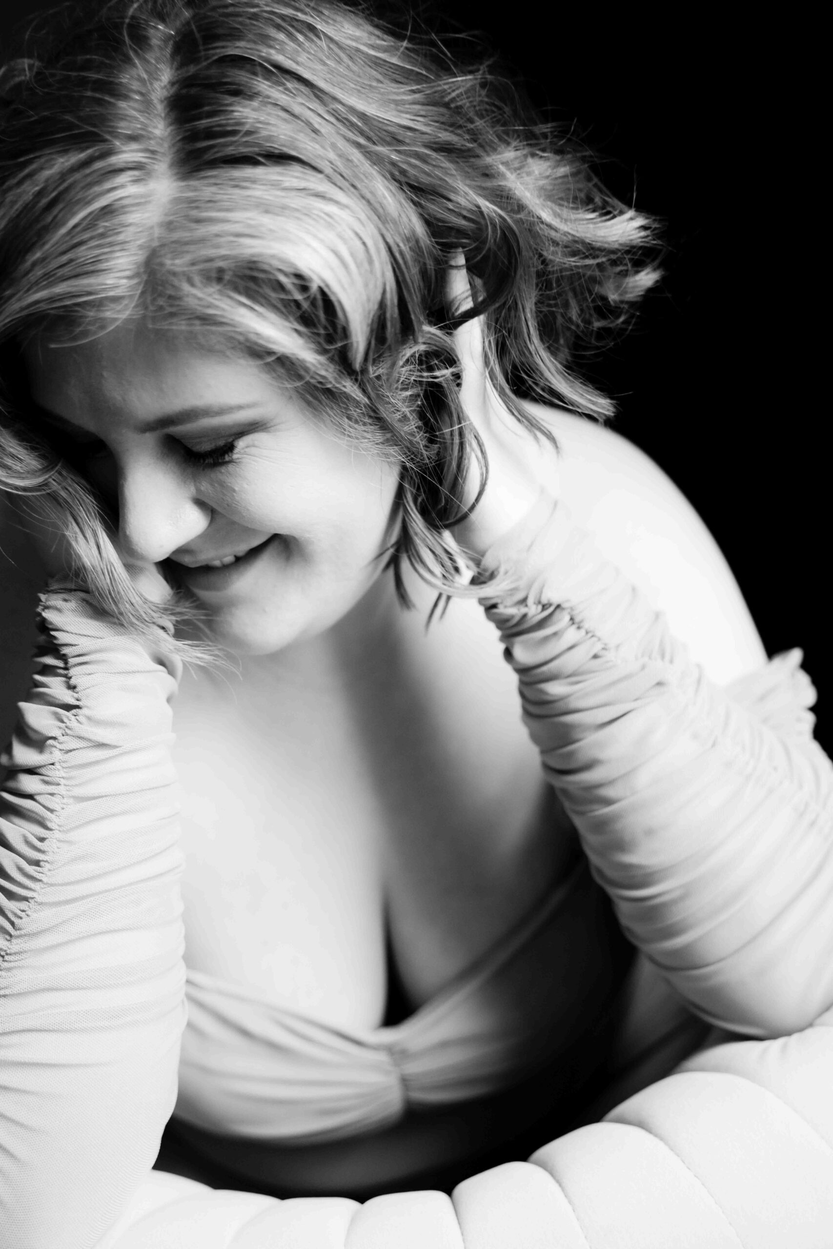 Black and white photo of a woman smiling, not looking at the camera.