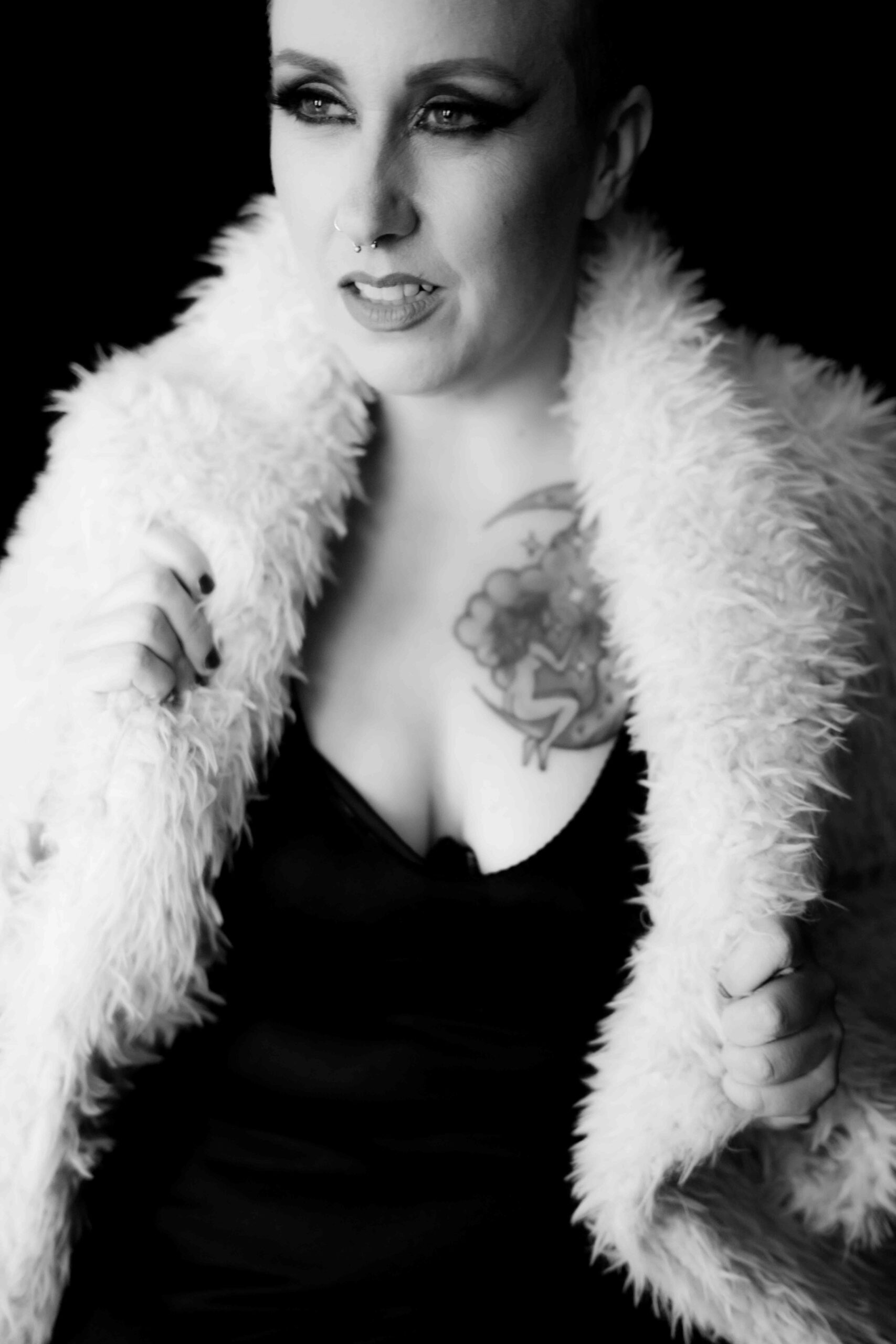 Black and white photo of a woman with huge tattoo on her chest wearing a boa