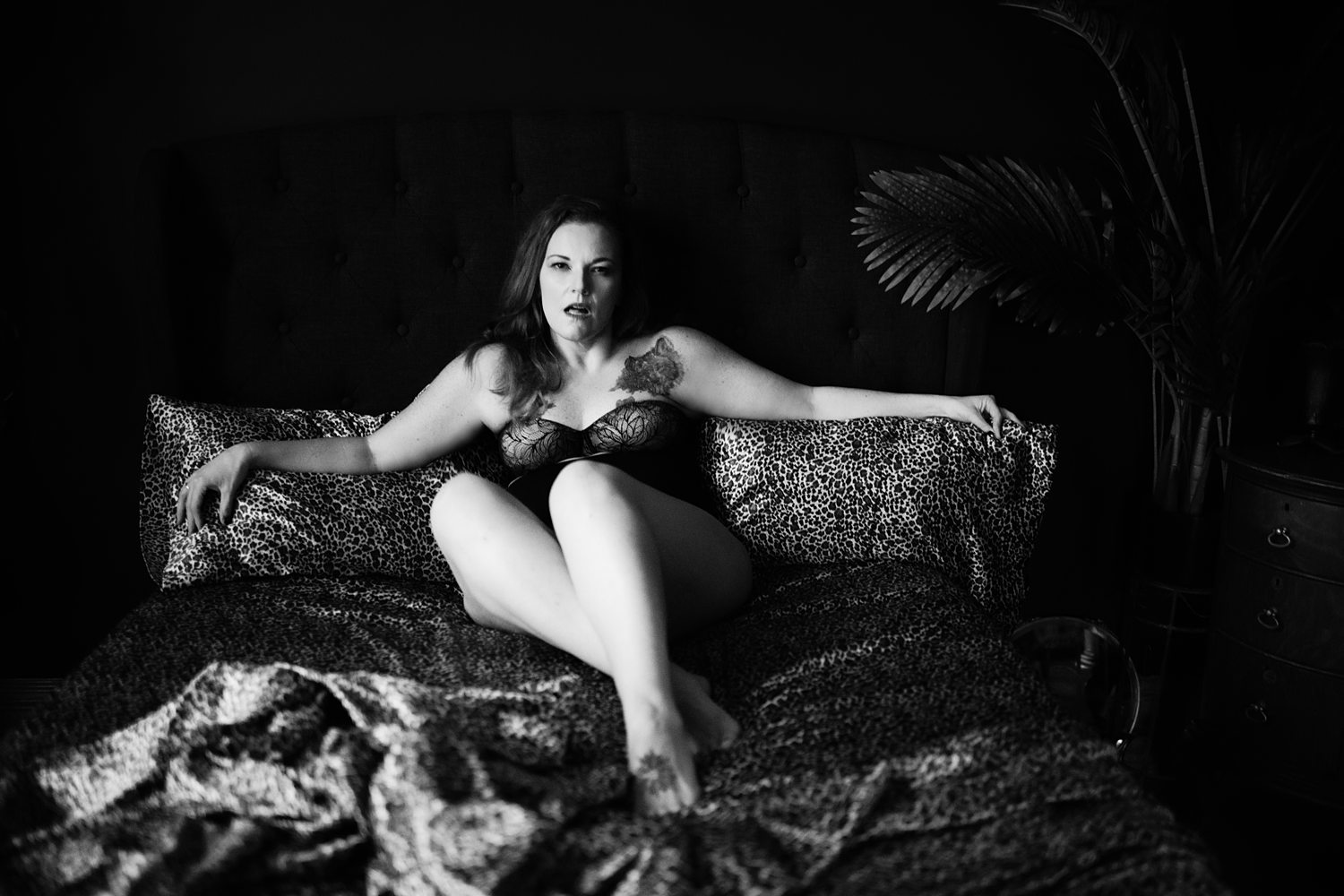 Dramatic photo of woman in black lingerie lying on leopard print sheets during self-discovery boudoir session in Kalamazoo.