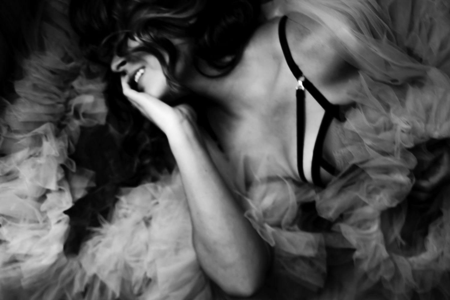 Elegant black-and-white boudoir portrait of woman surrounded by tulle from her luxury robe.